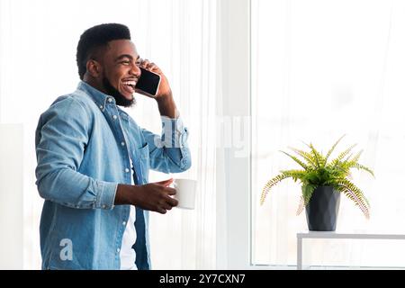 Junge fröhliche Geschäftsmann am Telefon sprechen und halten Kaffee Tasse Stockfoto