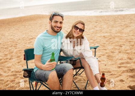 Ein glückliches Paar trinkt gemeinsam am Strand bei sonnigem Wetter Stockfoto