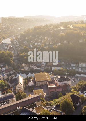 Blick aus der Vogelperspektive auf eine hügelige Stadt bei Sonnenuntergang, mit typischen Häusern und Straßen umgeben von grüner Vegetation und sanften Hügeln, Calw, Schwarzwald, Germa Stockfoto