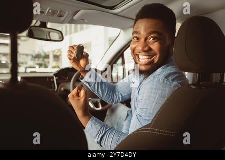 Mann Mit Neuem Autoschlüssel Gesturing Ja Im Auto Sitzen Stockfoto