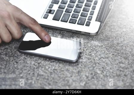 Zugeschnittenes Bild einer jungen Frau, die Anwendungen und Multimediaprogramme per Smartphone herunterlädt, mit Laptop auf der Straße in der modernen Stadt Stockfoto