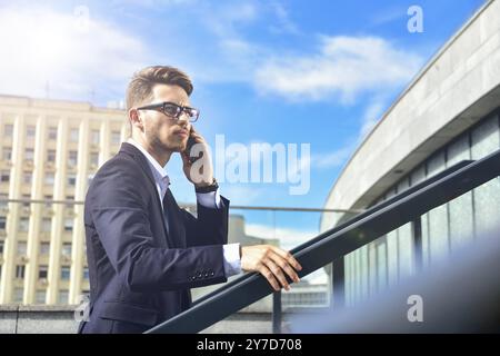 Hübscher erfolgreicher Geschäftsmann in elegantem Anzug im Freien, der auf der Straße in der Stadt spaziert Stockfoto