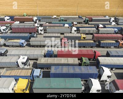 LKW in der Schlange, um Getreide im Hafen zu entladen. Luftaufnahme von vielen Lastwagen mit Anhängern Stockfoto