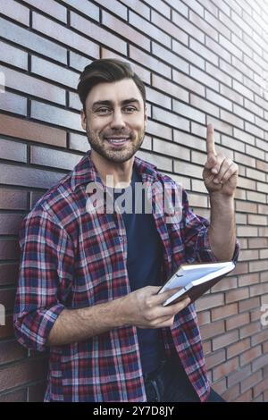 Porträt eines lächelnden gutaussehenden Mannes in Brille und Hemd isoliert auf brauner Ziegelwand Stockfoto