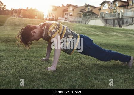 Sport. Athlet macht Liegestütze bei Sonnenuntergang im Park, dünner Kerl, der Sport macht und versucht, fit zu werden Stockfoto
