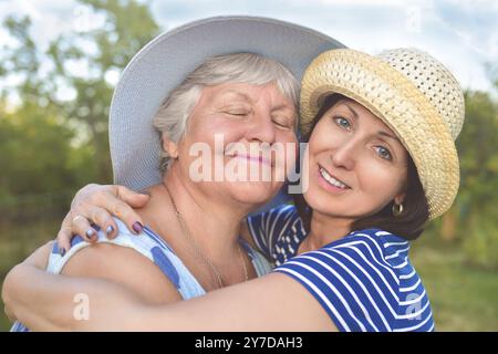 Glückliche Tochter, die ihre lächelnde Mutter umschließt Stockfoto