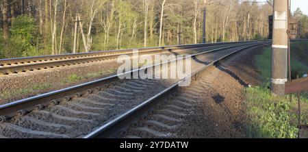 Panorama von zwei Bahngleisen an einer Wende durch den Wald. Die Straße, auf der Züge fahren, fährt mit der Bahn Stockfoto