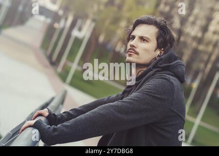 Porträt eines jungen Mannes, der Musik hört, auf der Brücke steht und die wunderschöne Aussicht genießt Stockfoto