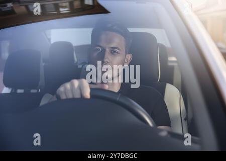 Gutaussehender Mann, der in einem Auto sitzt und das Lenkrad hält Stockfoto