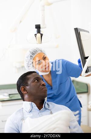 Zahnärztin zeigt auf das Display, um dem Patienten Informationen anzuzeigen Stockfoto