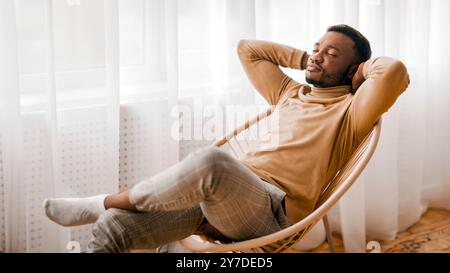 Mann auf Stuhl, Hände hinter dem Kopf zu Hause sitzen Stockfoto