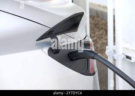 Coalinga, KALIFORNIEN - 29. Mai 2024: Nahaufnahme eines Tesla EV mit einem an einer Tesla Supercharger Station eingesteckten Ladekabel. Stockfoto