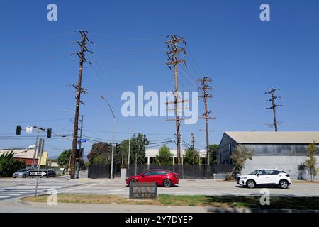 Fotos mit Stromleitungen, Straßenecken und Autos mit klarem blauen Himmel und städtischer Infrastruktur im Hintergrund. Stockfoto