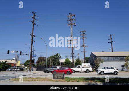 Fotos mit Stromleitungen, Straßenecken und Autos mit klarem blauen Himmel und städtischer Infrastruktur im Hintergrund. Stockfoto