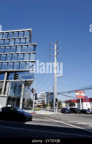 Fotos mit Stromleitungen, Straßenecken und Autos mit klarem blauen Himmel und städtischer Infrastruktur im Hintergrund. Stockfoto