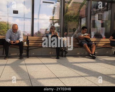 Fremde vertieften sich am Bahnhof Summit, New Jersey, in ihre Handys, während sie sich der Umgebung nicht bewusst waren. Stockfoto