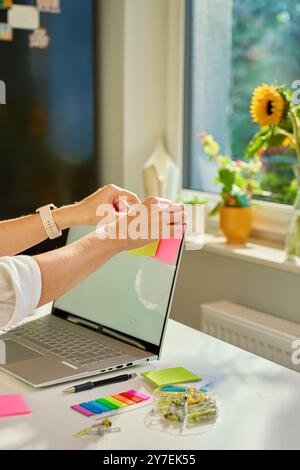 Frau verwendet Haftnotizen auf ihrem Laptop-Bildschirm, um ihre Arbeit zu organisieren, während sie von zu Hause aus arbeitet. Konzept der Planung und des Aufgabenmanagements in OFF Stockfoto