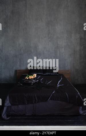 Bett mit schwarzer Bettwäsche im grauen Schlafzimmer Stockfoto