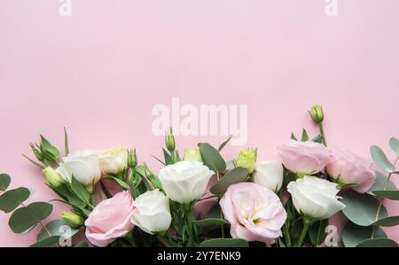 Eine Kollektion pastellfarbener Rosen in Rosa- und Weißtönen, umgeben von frischem Grün, schafft eine ruhige und elegante Präsentation vor einem weichen rosa Hintergrund Stockfoto