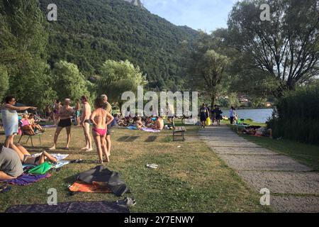 Monasterolo al Castello, Italien - August 2024 - Menschen, die sich auf einem Rasen sonnen und bei Sonnenuntergang am Seeufer schwimmen Stockfoto