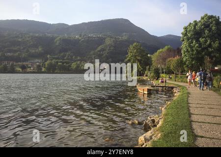 Monasterolo al Castello, Italien - August 2024 - Menschen, die bei Sonnenuntergang am Seeufer vorbeischlendern Stockfoto