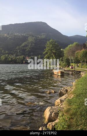 Monasterolo al Castello, Italien - August 2024 - Menschen, die bei Sonnenuntergang am Seeufer vorbeischlendern Stockfoto