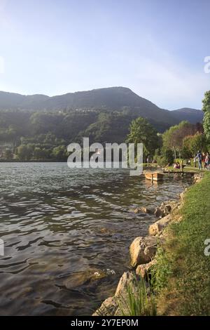 Monasterolo al Castello, Italien - August 2024 - Menschen, die bei Sonnenuntergang am Seeufer vorbeischlendern Stockfoto