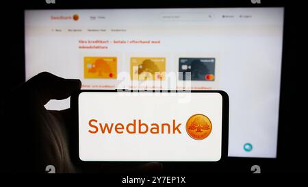 Deutschland. September 2024. In dieser Abbildung hält eine Person ein Mobiltelefon mit dem Logo des schwedischen Finanzdienstleisters Swedbank ab vor der Webseite. Quelle: SOPA Images Limited/Alamy Live News Stockfoto