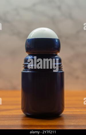 Blaue Anti-Transpirant-Flasche zum Aufrollen auf Holzoberfläche, vor hellem Hintergrund. Schlankes und funktionales Design. Stockfoto