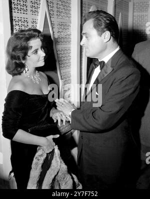 Der Impressario Mike Todd tauscht ein paar coole Worte mit seiner glamourösen Frau, der Schauspielerin Elizabeth Taylor, aus, als sie eine Weile die Hände schnappen, als sie den Kostümball in Hollywood besuchten. 30. Oktober 1957. Stockfoto