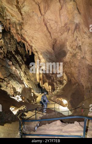 Ein Mann in Tarnkleidung läuft durch eine Höhle. Die Höhle ist dunkel und hat einen feuchten, erdigen Geruch. Der Mann hält einen Rucksack und das ist er Stockfoto