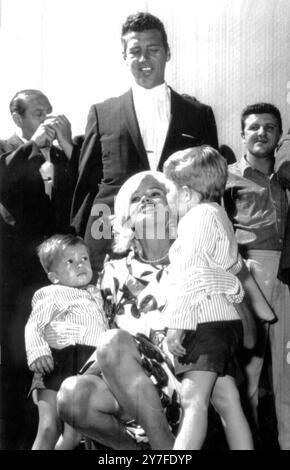 Jayne Mansfield bekommt einen Kuss von ihrem kleinen Sohn Miklos, 3, während sein Bruder Zoltan zusieht, als sie am Flughafen Fiumicino ankam, um mit Maurice Chevalier und Eleanor Parker an einem neuen Film zu arbeiten. Hinter der Schauspielerin steht ihr Ehemann Mickey Hargitay. Anfang des Monats reichte Miss Mansfield eine Scheidungsklage vor dem Santa Monica Superior Court ein, in der sie extreme geistige Grausamkeit und schweres geistiges Leid gegen ihren Mann beschuldigte. Mai 1962 Stockfoto