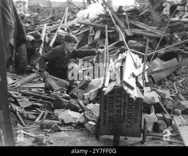 Ronald Spanner, 11 Jahre alt aus Lambeth, verbringt seine Freizeit damit, Geld für die Londoner Kriegswaffenwoche und andere gute Zwecke zu sammeln. Ronald war auf die Idee gekommen, Holz aus bombardierten Häusern zu sammeln, es zu hacken und es als Brennholz an seine Nachbarn zu verkaufen, um Geld zu sammeln. Stockfoto