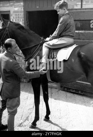 Lester Piggott steigt mit der Sonne auf und verbringt zwei Stunden vor dem Frühstück mit dem Reiten. Lester ist der jüngste Jockey Großbritanniens, der ein Rennen gewonnen hat, und wann immer er Freizeit hat, ist er mit den Pferden seines Vaters bei seinem Haus in Lambourn, Berkshire. Hier zeigt ihm der Trainer von Lester's Vater die richtige Position im Sattel. August 1948 Stockfoto