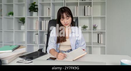 Junge Schüler, die in Online-Studien und Notizen eingetaucht sind Stockfoto