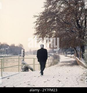 Ein einsamer Mann, der nach einem Schneefall auf dem Schleppweg in Richmond, Surrey, England spaziert Stockfoto