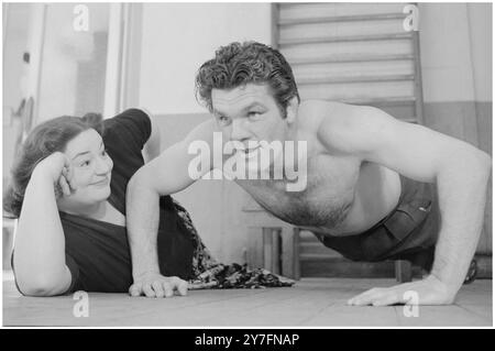 Hattie Jacques und Freddie Mills London 1955. 1955 war Hattie Großbritanniens beliebteste Comedienne und Freddie war Großbritanniens Sportidol. Von 1948 bis 1950 war er Weltmeister im Leichtgewicht und begann eine Karriere im Film- und Fernsehbereich. Hier soll er Hatties persönlicher Trainer sein, aber sie interessiert sich deutlich mehr für seine bauchmuskulatur als für die Übung. Sie könnte es sich leisten, Witze über das Fitnessstudio zu machen. Sie war immer eine sehr große Dame, aber das störte nie ihren riesigen Erfolg auf Bühne, Radio und Leinwand als Comedy-Schauspielerin. Sie war vor allem für ihre Rollen in 14 Filmen bekannt (insbesondere in den Filmen) Stockfoto