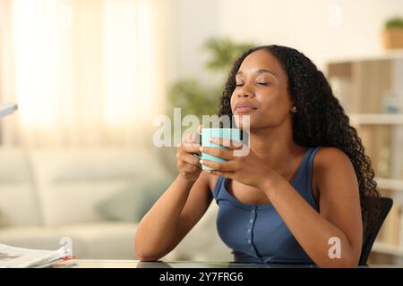 Schwarze Frau, die zu Hause nach Kaffee- oder Teearoma riecht Stockfoto