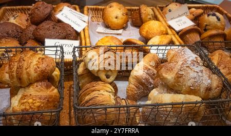 Bistro mit Regalen mit frischen Croissants. Verschiedene Gebäckstücke, die auf einem Tablett in einer Bäckerei verkauft werden. Nahaufnahme des appetitlichen goldenen Croissants Stockfoto