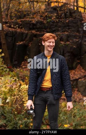 Ein junger Mann steht in einem bunten Herbstwald Stockfoto