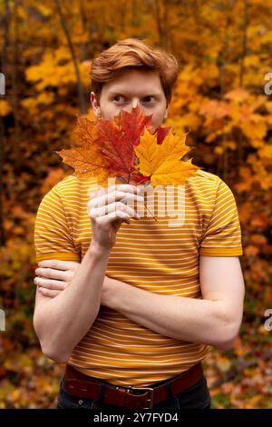 Mann mit rotem Haar in einem Wald voller bunter Herbstblätter Stockfoto