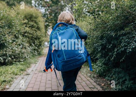 Kleiner Junge mit Rucksack, der zur Schule geht, Rückansicht Stockfoto