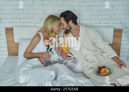 Junges, liebevolles Paar, das sich beim Frühstück im Bett verbündet Stockfoto