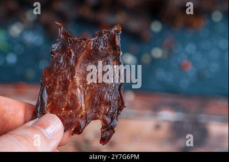 Ein kleines Stück traditionelles Rindfleisch wird in der Hand gehalten. Das Bild erfasst eine detaillierte Makroansicht aus der Perspektive des Halters. Stockfoto