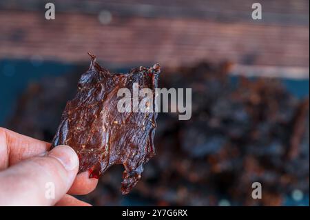 Ein kleines Stück traditionelles Rindfleisch wird in der Hand gehalten. Das Bild erfasst eine detaillierte Makroansicht aus der Perspektive des Halters. Stockfoto