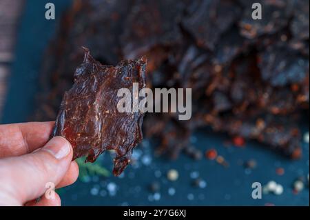 Ein kleines Stück traditionelles Rindfleisch wird in der Hand gehalten. Das Bild erfasst eine detaillierte Makroansicht aus der Perspektive des Halters. Stockfoto