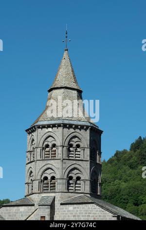 Glockenturm der Basilika Notre-Dame d'Orcival mit romanischer Architektur unter klarem blauen Himmel, Puy de Dome, Auvergne-Rhone-Alpes, Frankreich Stockfoto