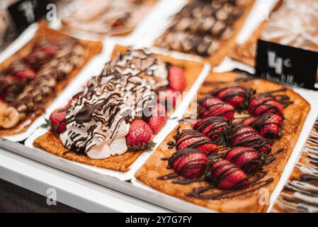 Ein Schaufenster zeigt eine Vielzahl von Erdbeerdesserts mit Schokolade und Schlagsahne. Das Display bietet eine Reihe köstlicher Leckereien, Stockfoto