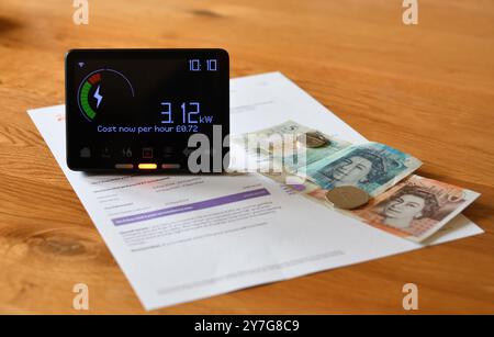 Smart Meter in Home Display (IHD) auf Holztisch, der den aktuellen Verbrauch in Kilowatt und die Kosten pro Stunde anzeigt Stockfoto