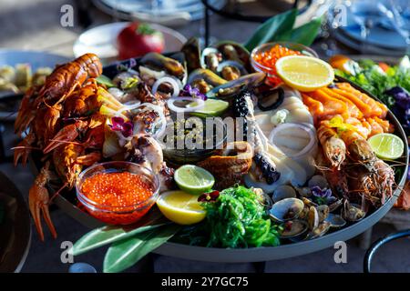 Eine lebendige Meeresfrüchte-Platte mit Hummer, Garnelen, Venusmuscheln, Lachs und verschiedenen Beilagen, wunderschön auf einem Tisch angeordnet. Stockfoto